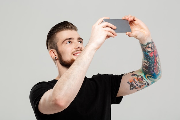 Free Photo young handsome man looking at phone over grey wall.