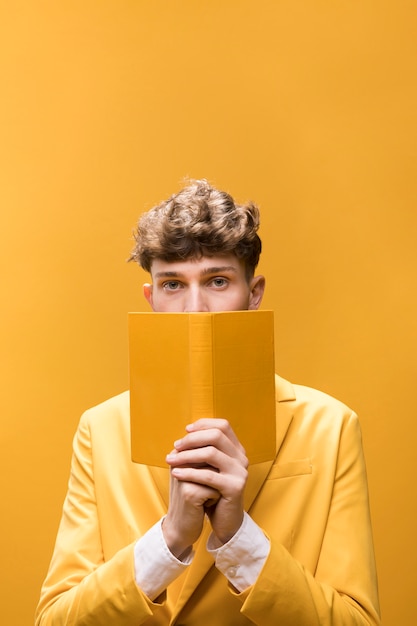 Free Photo young handsome man reading a book in a yellow scene