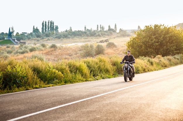 Free photo young handsome man riding on motorbike at countryside road.