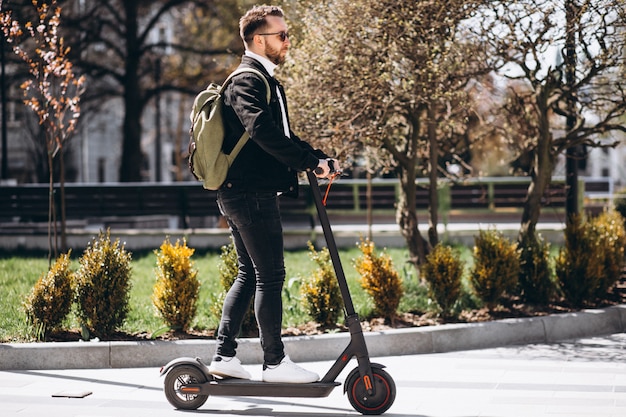 Free photo young handsome man riding on scooter in the park