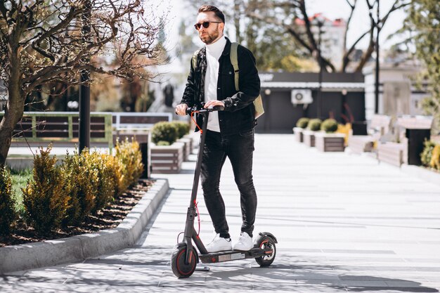 Young handsome man riding on scooter in the park