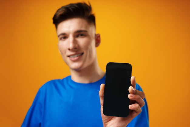 Young handsome man showing black smartphone screen