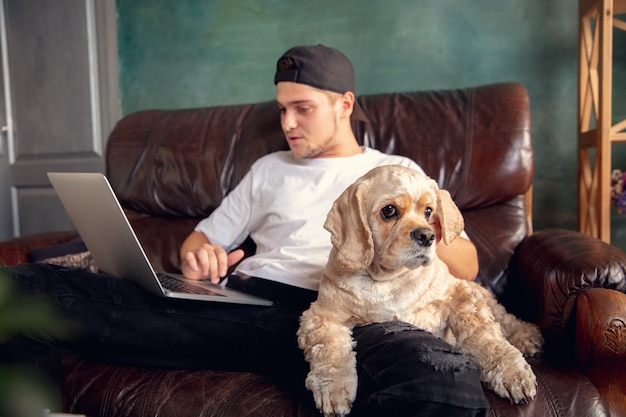 Free photo young handsome man sitting and working at home with his cute dog.