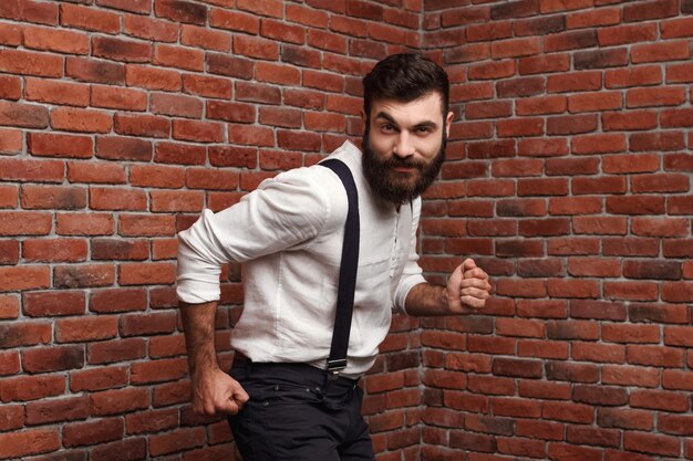 Young handsome man smiling dancing posing on brick wall.