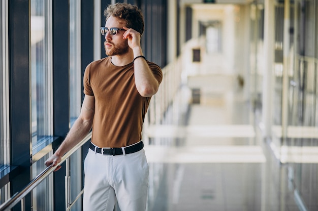 Free photo young handsome man standing by the window at the airport