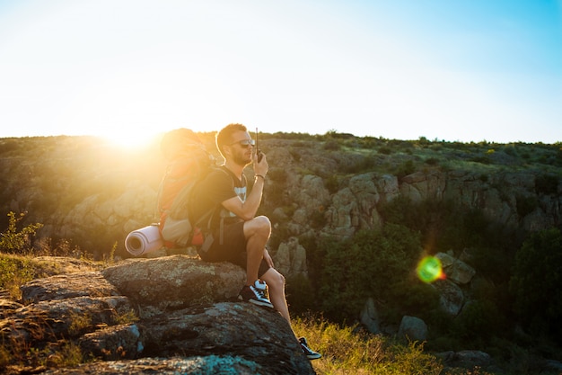 Free photo young handsome man talking on walkie talkie radio, enjoying canyon view