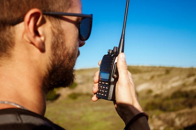 Young handsome man talking on walkie talkie radio, enjoying canyon view