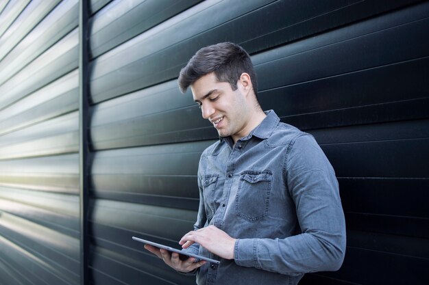 Young handsome man typing on his tablet computer