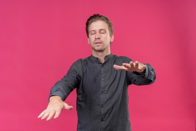 Young handsome man walking with closed eyes holding out his hands