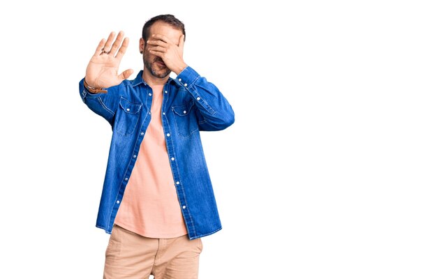 Young handsome man wearing casual clothes covering eyes with hands and doing stop gesture with sad and fear expression. embarrassed and negative concept.