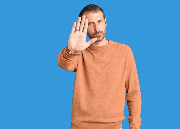 Young handsome man wearing casual clothes doing stop sing with palm of the hand. warning expression with negative and serious gesture on the face.