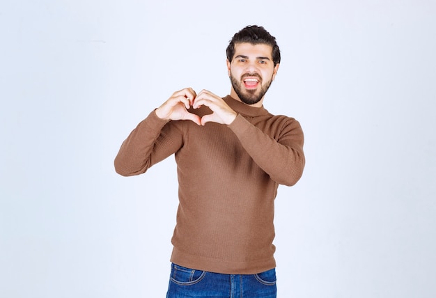 Free photo young handsome man wearing casual clothes smiling and doing heart symbol shape with hands. high quality photo