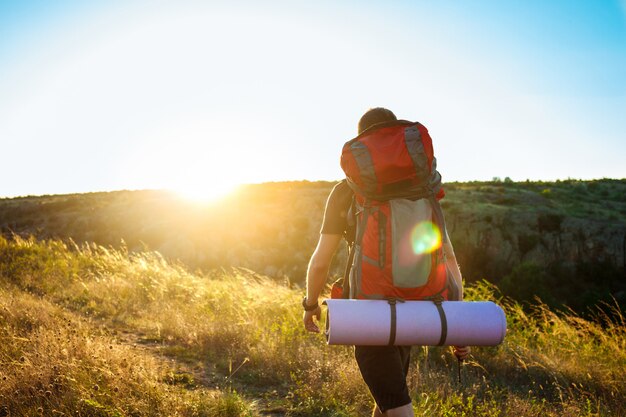 Young handsome man with backpack traveling in canyon at sunset