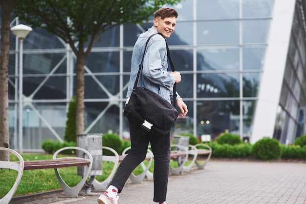 Young handsome man with a bag on his shoulder in a hurry to the airport.