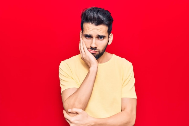 Young handsome man with beard wearing casual t-shirt thinking looking tired and bored with depression problems with crossed arms.