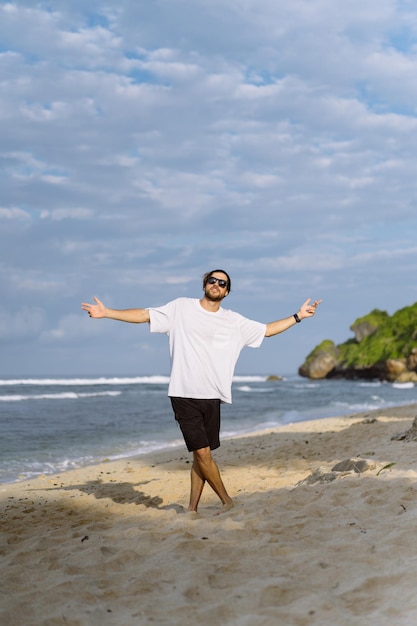 Young handsome man with a charming smile in sunglasses on the beach.