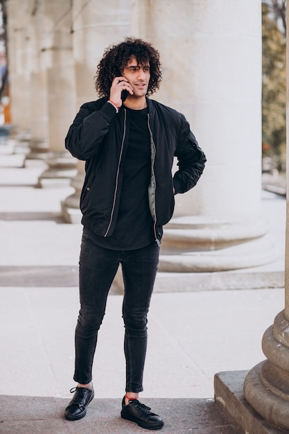 Young handsome man with curly hair talking on the phone