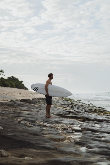 Young handsome man with a surfboard on the ocean.