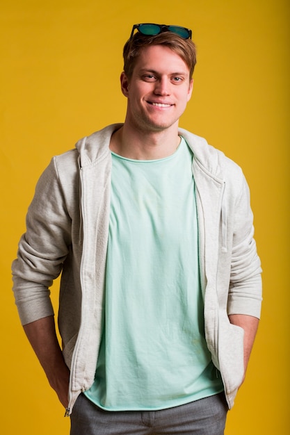 Free photo young handsome man with wearing casual t-shirt standing over yellow wall looking with smile on face, natural expression. laughing confident.