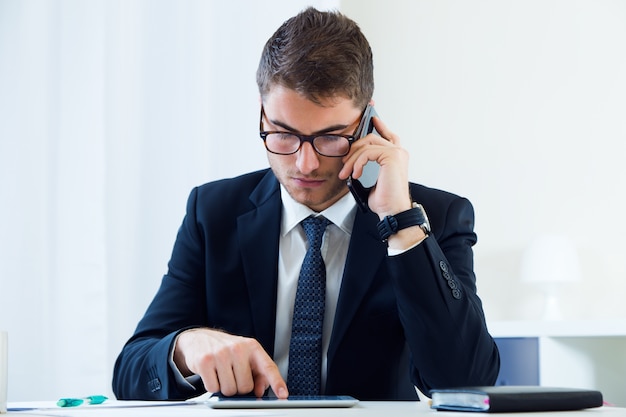 Young handsome man working in his office with mobile phone.