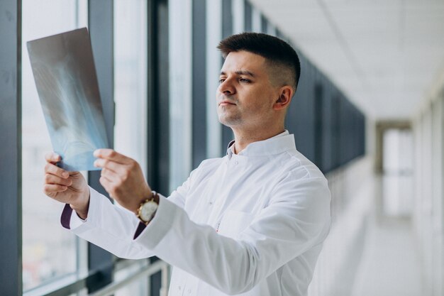 Young handsome surgeon looking at the x-ray