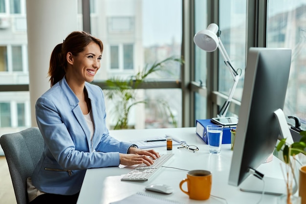 Free photo young happy businesswoman using desktop pc while working in the office