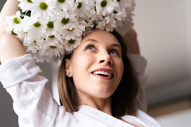 Young happy cheerful sweet lovely smiling woman enjoy a bouquet of white fresh flowers