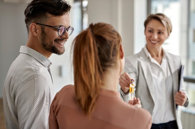 Free photo young happy couple buying a new home and receiving key from their real estate agent