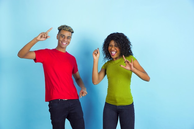 Young happy couple in casual clothes posing on blue wall