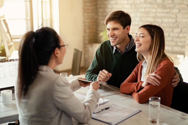 Young happy couple communicating with financial advisor who is using digital tablet during a meeting