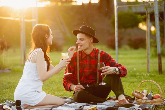 Young and happy couple enjoying a picnic spread on parkside in summer day