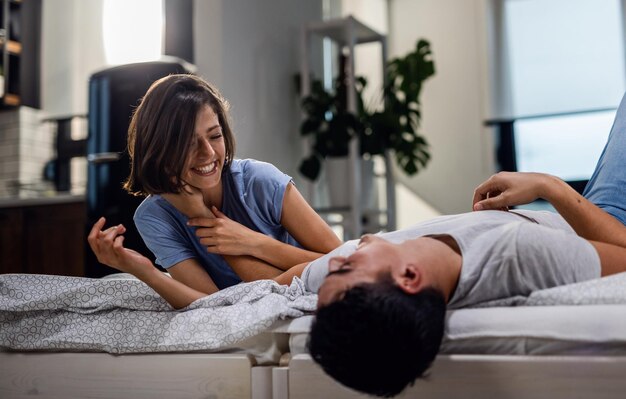 Young happy couple having fun together while lying on the bed and communicating