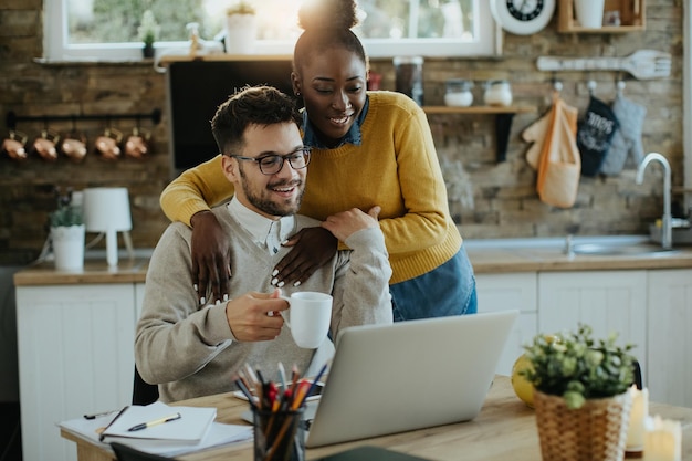 Young happy couple reading an email on laptop at home