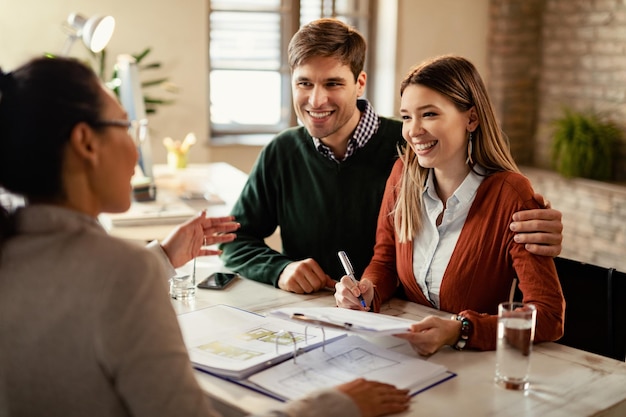 Free photo young happy couple signing a contract while being on a meeting with insurance agent in the office