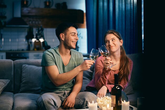 Young happy couple toasting with wine in the evening at home