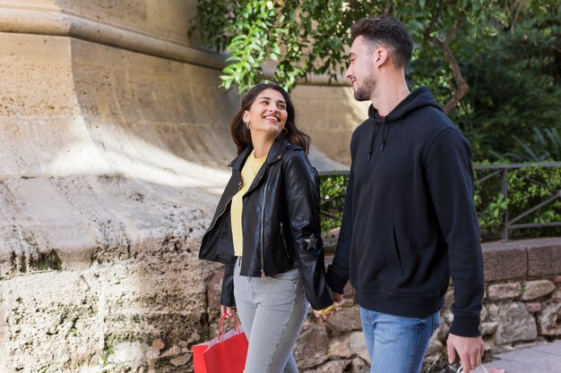 Young happy couple walking on street near plants