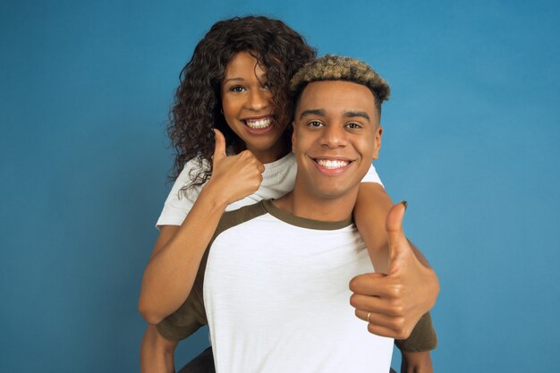 Young happy couple in white casual clothes posing on blue wall