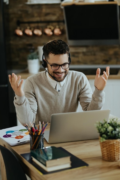 Young happy entrepreneur having video call over a computer at home