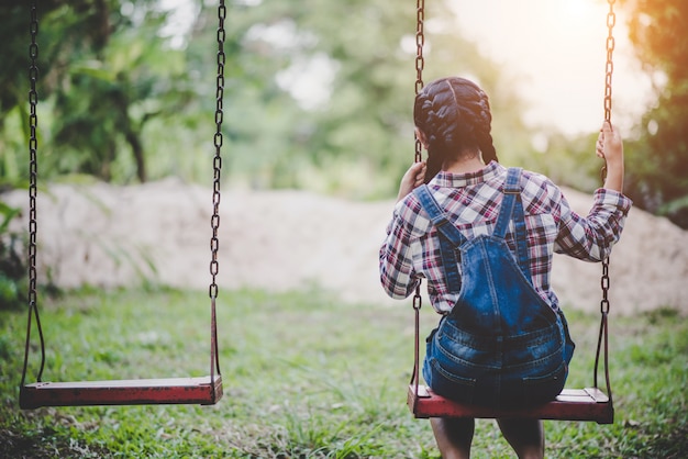 Free photo young happy girl riding on a swing in the park