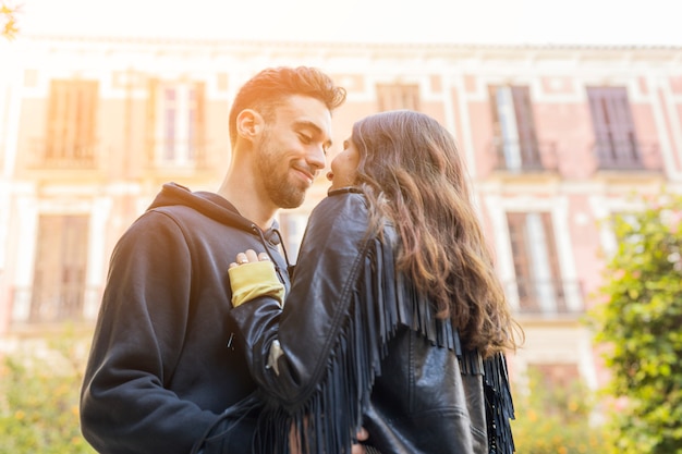 Young happy guy hugging lady near building 