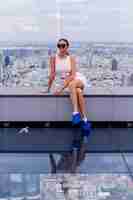 Free photo young happy smiling caucasian woman traveller in fitting dress and sunglasses on high floor in bangkok