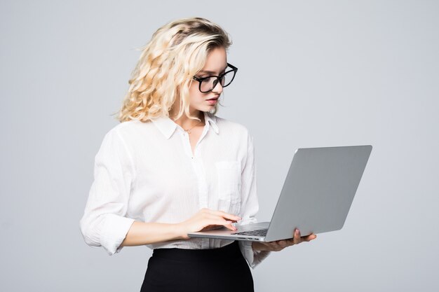 Young happy smiling woman in casual clothes holding laptop and sending email to her best friend