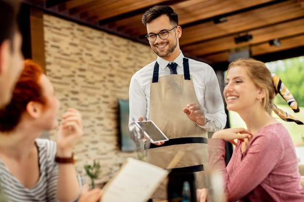 Free Photo young happy waiter taking order from his guests in a cafe