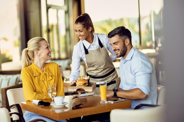 Young happy waitress serving food to guests in a restaurant