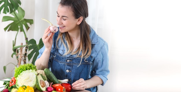 Free photo young and happy woman eating salad at the table ,on a light background in denim clothes. the concept of a healthy home-made food. place for text .