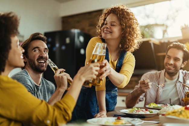 Young happy woman having fun while toasting with her friends during a lunch at dining table