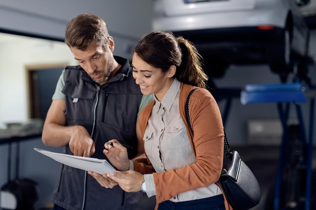 Free photo young happy woman signing paperwork at auto repair shop