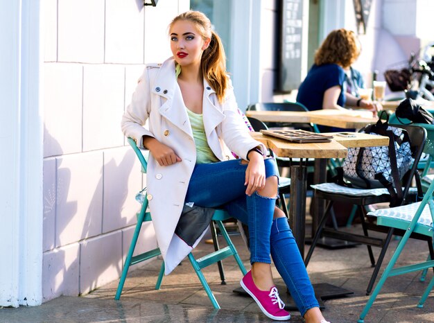 Young happy woman smiling and relaxing at city cafe terrace, sunny weather, bright make up , stylish casual outfit, holidays, travel, vacation, joy.