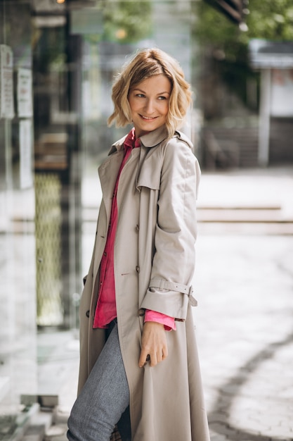 Free photo young happy woman in spring coat out in the city