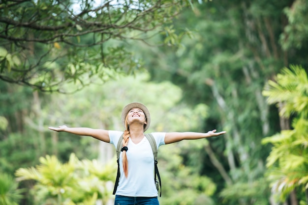 Young happy woman with backpack raising hand enjoy with nature. 